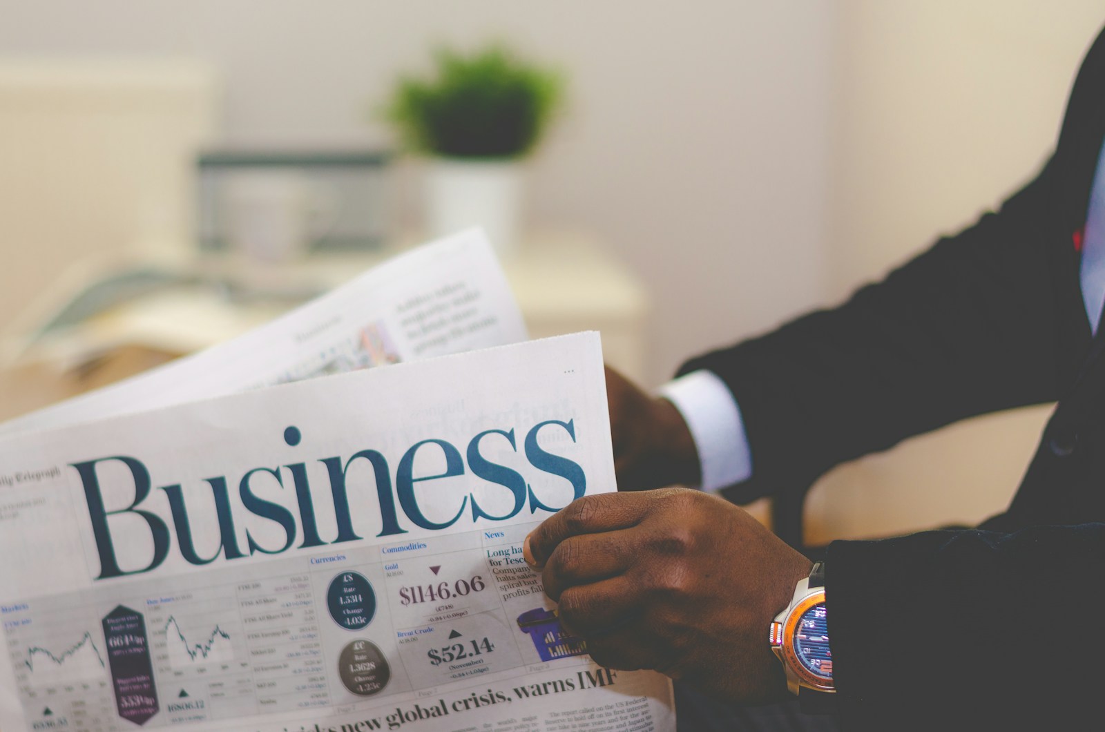 A person in a suit reading the business section of a newspaper.